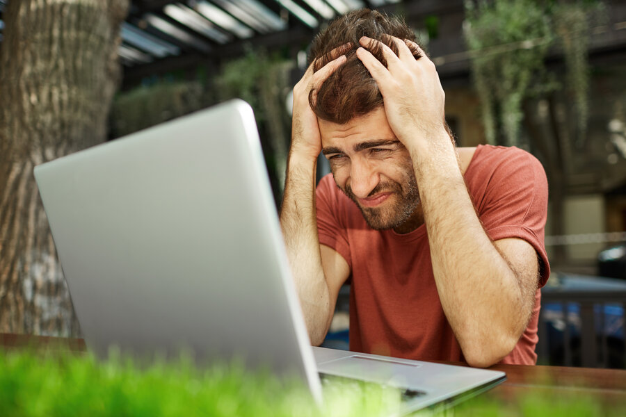 Outdoor portrait of tired overworked young businessman feeling stressed while facing a problem, doing accounts and calculating expenses by himself, squeezing his head. People and business.